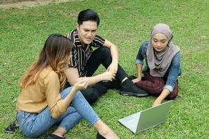 Young Asian different ethnic malay chinse  man woman activity lifestyle student educating job business sit on grass discuss photo