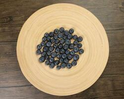 Fresh ripe deep purple Blueberry on old wooden plate macro closeup top view photo