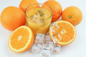 Fresh yellow orange juice in glass with whole sliced orange fruit and ice cube on white background photo