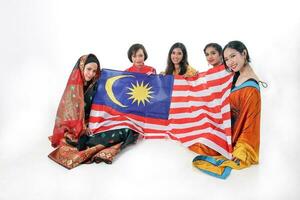 South east Asian Malay Chinese Indian race ethnic origin woman wearing dress costume baju kurung cheongsam samfu kebaya Sharee multiracial community holding Malaysian flag Jalur Gemilang photo