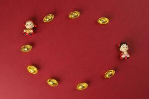 Chinese boy girl doll figurine money syce ingot gold on red background copy space photo