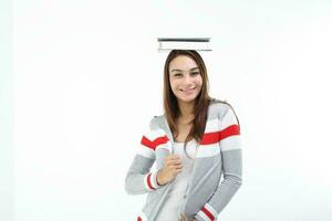 yong asiático juventud niña en casual vestir equilibrio libro en cabeza Mira a cámara expresión sonrisa contento gracioso cara en blanco antecedentes foto