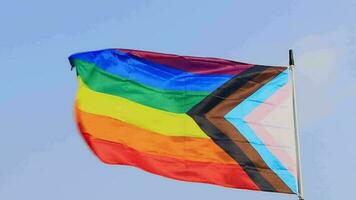 Rainbow LGBT flag flutters atop the pole in the background of the sunset sky video
