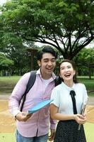 joven asiático malayo chino hombre mujer al aire libre parque libro archivo carpeta ordenador portátil computadora teléfono sentar estar estudiar mezclarse foto