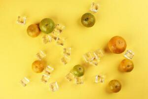 small yellow green mandarin ice cube orange on yellow colour paper background copy space for text photo