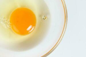 Raw Egg Yolk and white liquid in transparent glass bowl white background photo