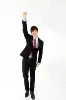 Young smart handsome Asian man business office wearing suit tie on white background look at camera walk forward fist up joy success photo