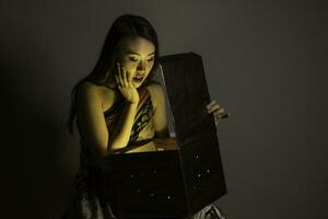 Asian woman opening mystic book box magical light dark background photo