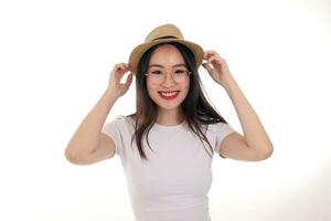 Beautiful young south east Asian woman wearing eyewear golden frame glasses hat pose fashion style white background look around copy text space hands on hat photo