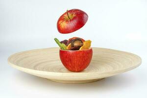 Healthy vegetable chips yellow sweet potato purple carrot green radish green beans and shiitake mushrooms in hollow red apple white background wooden plate photo