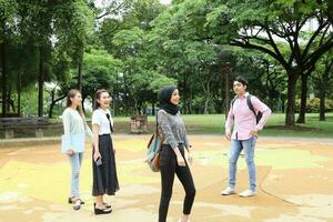 joven asiático malayo chino hombre mujer al aire libre parque libro archivo carpeta ordenador portátil computadora teléfono sentar estar estudiar mezclarse foto