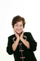 Elderly asian Chinese female wearing black tang samfu on white background pretty sweet smile hand on cheek photo