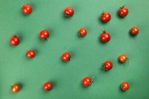 Red ripe cherry tomato with stem on green paper background copy text space photo