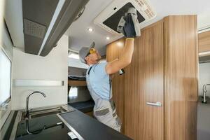 RV Rental Company Worker Cleaning Motorhome Air Condition Unit photo