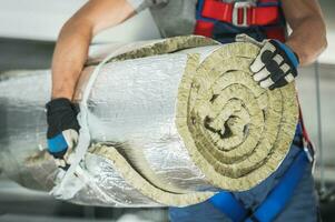 Contractor Worker with Roll of Mineral Wool Insulation photo