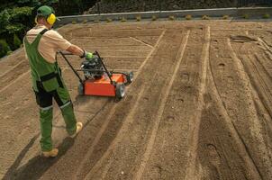 Landscaping Worker Preparing Backyard Garden Soil Using Aerator photo