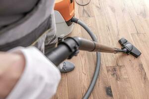 Male Worker Vacuuming Hardwood Flooring. photo