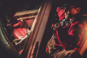 Red Suit and Cowboy Hat Wearing Men Inside Classic Car photo