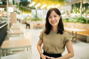 Smiling beautiful asian woman standing in cafeteria at shopping mall. photo