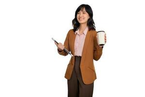 Beautiful smiling young asian businesswoman carrying laptop computer and cup of coffee to go while standing isolated over white background photo