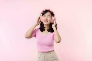 Smile pretty model person listen music song and enjoy dance with wireless headphone online audio radio sound. Positive fun exited joyful youth female woman sing on pink isolated background studio photo