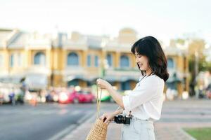 Portrait beautiful asian woman traveler with camera explore street on summer vacation in Bangkok, Thailand photo