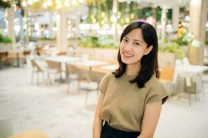 Smiling beautiful asian woman standing in cafeteria at shopping mall. photo