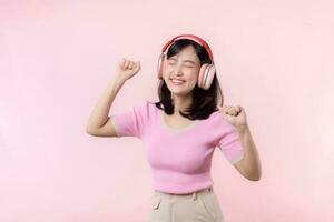 Smile pretty model person listen music song and enjoy dance with wireless headphone online audio radio sound. Positive fun exited joyful youth female woman sing on pink isolated background studio photo