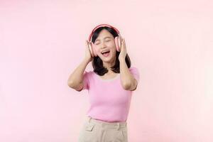 Smile pretty model person listen music song and enjoy dance with wireless headphone online audio radio sound. Positive fun exited joyful youth female woman sing on pink isolated background studio photo