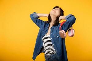 Fashion portrait young asian woman wearing denim clothes, red glasses and headphone isolated on yellow background. Lifestyle people concept. photo