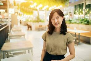 Smiling beautiful asian woman standing in cafeteria at shopping mall. photo