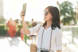 Portrait young beautiful asian woman using smartphone to video call with friend and explore street on summer vacation in Bangkok, Thailand photo