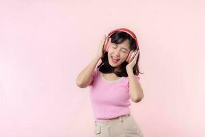 sonrisa bonito modelo persona escucha música canción y disfrutar danza con inalámbrico auricular en línea audio radio sonido. positivo divertido salido alegre juventud hembra mujer canta en rosado aislado antecedentes estudio foto