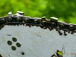 Sharpened sharp teeth of an electric saw chain on a blurred green background. photo