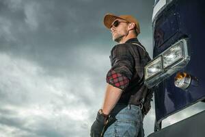 Caucasian Trucker Driver in Front of His Retro Semi Truck photo