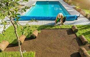 jardinero instalando rodar fuera césped siguiente a piscina foto