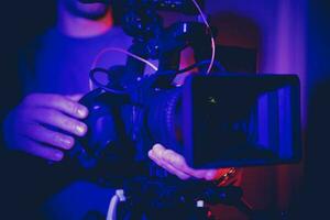 Profession Video Camera in Operators Hands Inside Dark Blue Illuminated Room photo