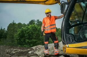 Machine Operator Standing On Hydraulic Excavator Assessing Job Site. photo