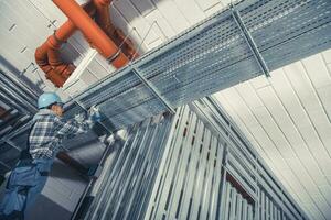 Technician Installing Electric Lines Along Aluminium Elements in a Commercial Building photo