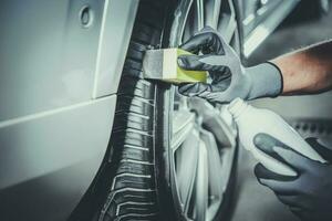 Car Detailing Worker Taking Care of Vehicle Tires and Alloy Wheels photo