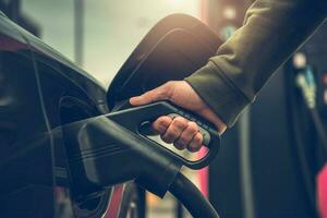 hombres cargando su ev eléctrico vehículo a cargando estación foto