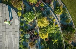 Residential Rockery Backyard Garden and Man Blowing Leaves From a Path photo