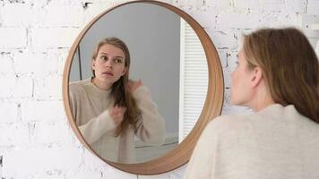 femme à la recherche à le miroir, fabrication en haut dans le Matin. Jeune millénaire femme Faire sa Matin routine à le chambre video