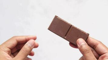 mano sostener un oscuro chocolate en contra blanco antecedentes video