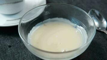 Falling condensed milk in a bowl close up video