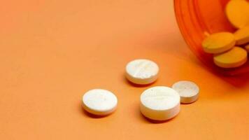 white color medical pills spilling on orange background video