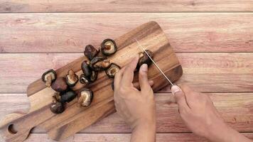 Mens hand- snijdend rauw champignon paddestoel Aan een hakken bord Aan tafel video