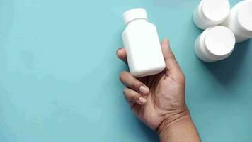 Young man hand holding a pill container on blue video