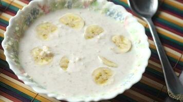 healthy breakfast with oats flakes and banana on table, top down video