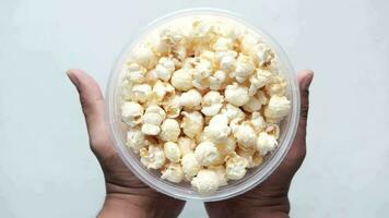 Young man eating popcorn from a container on black background video